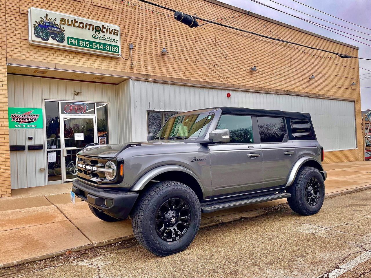 Gray off-road SUV parked outside a storefront on a wet street