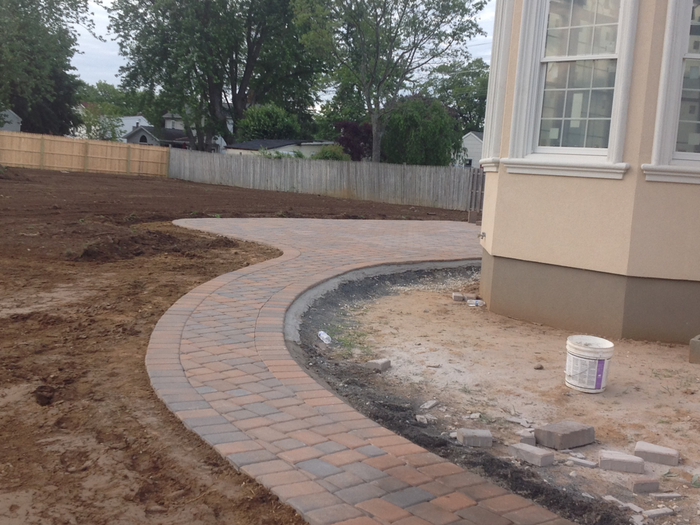 A brick walkway is being built in front of a house.