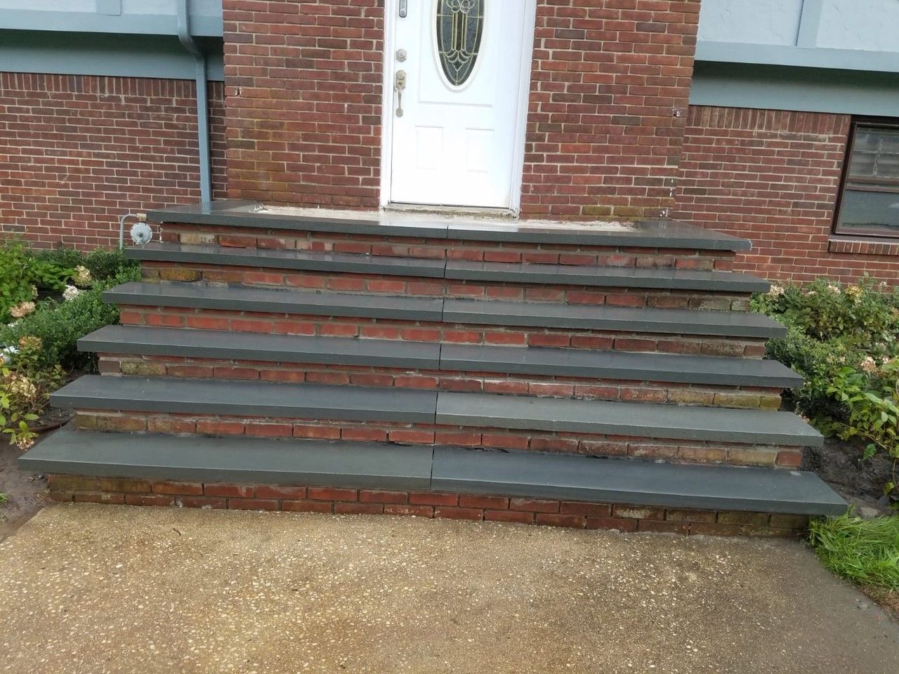 A set of stairs leading up to a brick house with a white door.
