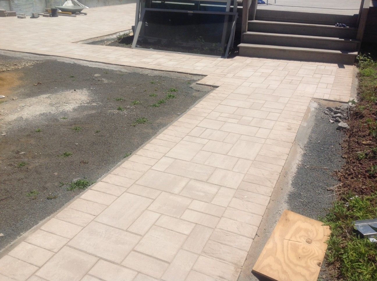 A brick walkway is being built next to a pool.