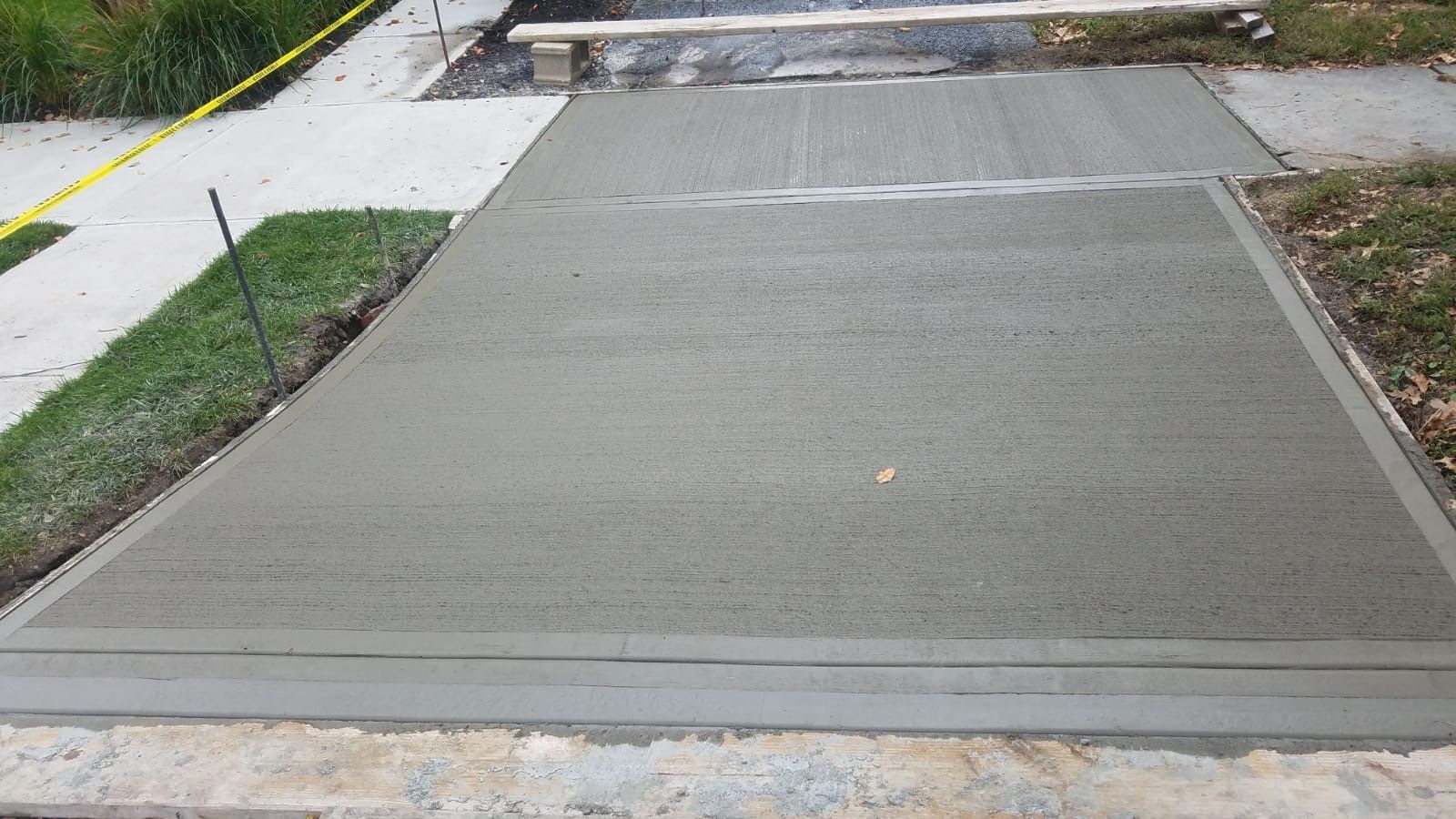 A concrete driveway is being built next to a sidewalk.