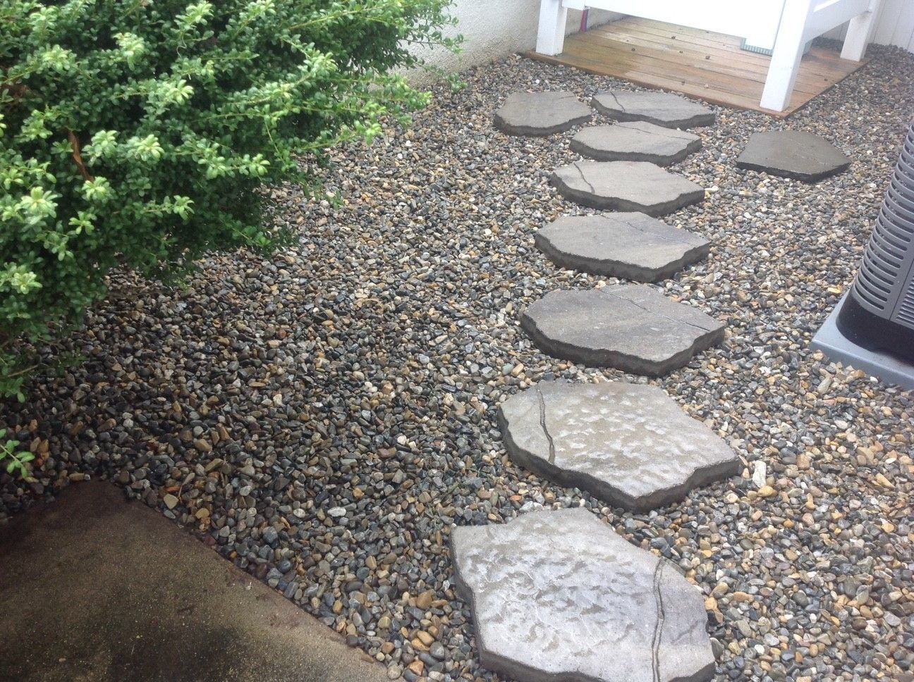 A row of stepping stones leading to a bench in a gravel area.