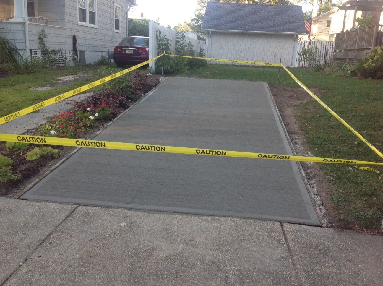 A concrete driveway is surrounded by caution tape