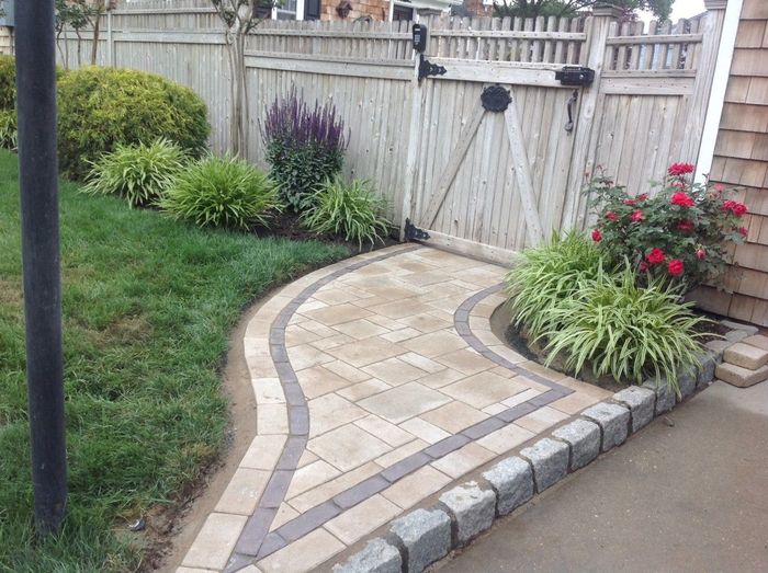 A brick walkway leading to a wooden gate in a yard.