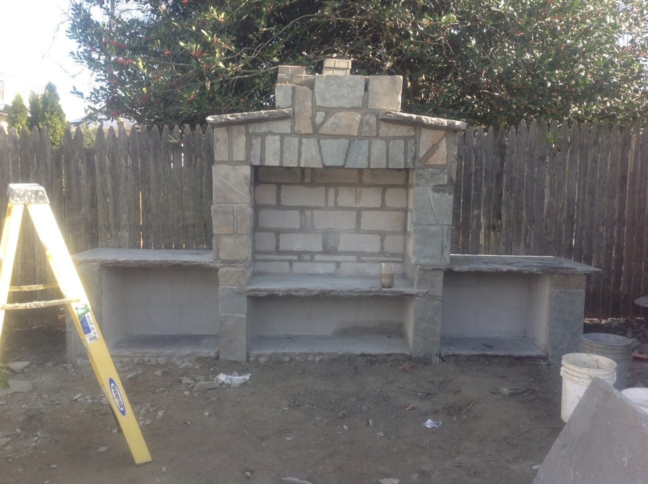 A ladder is sitting next to a brick fireplace being built