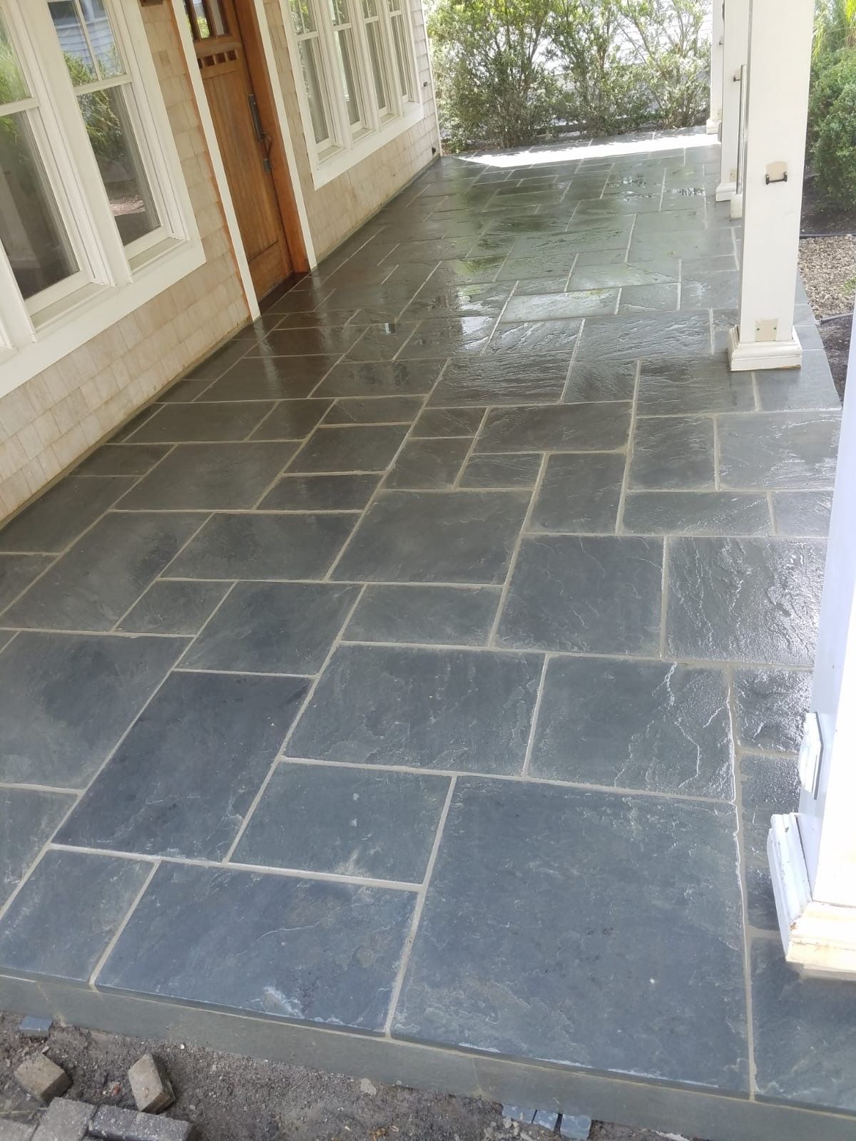 A porch with a black tile floor and a white door