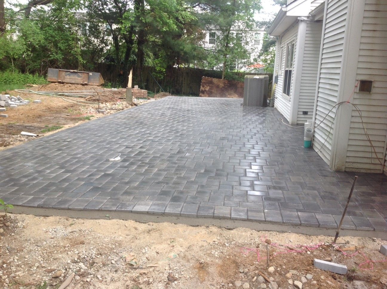 A brick driveway is being built in front of a house.