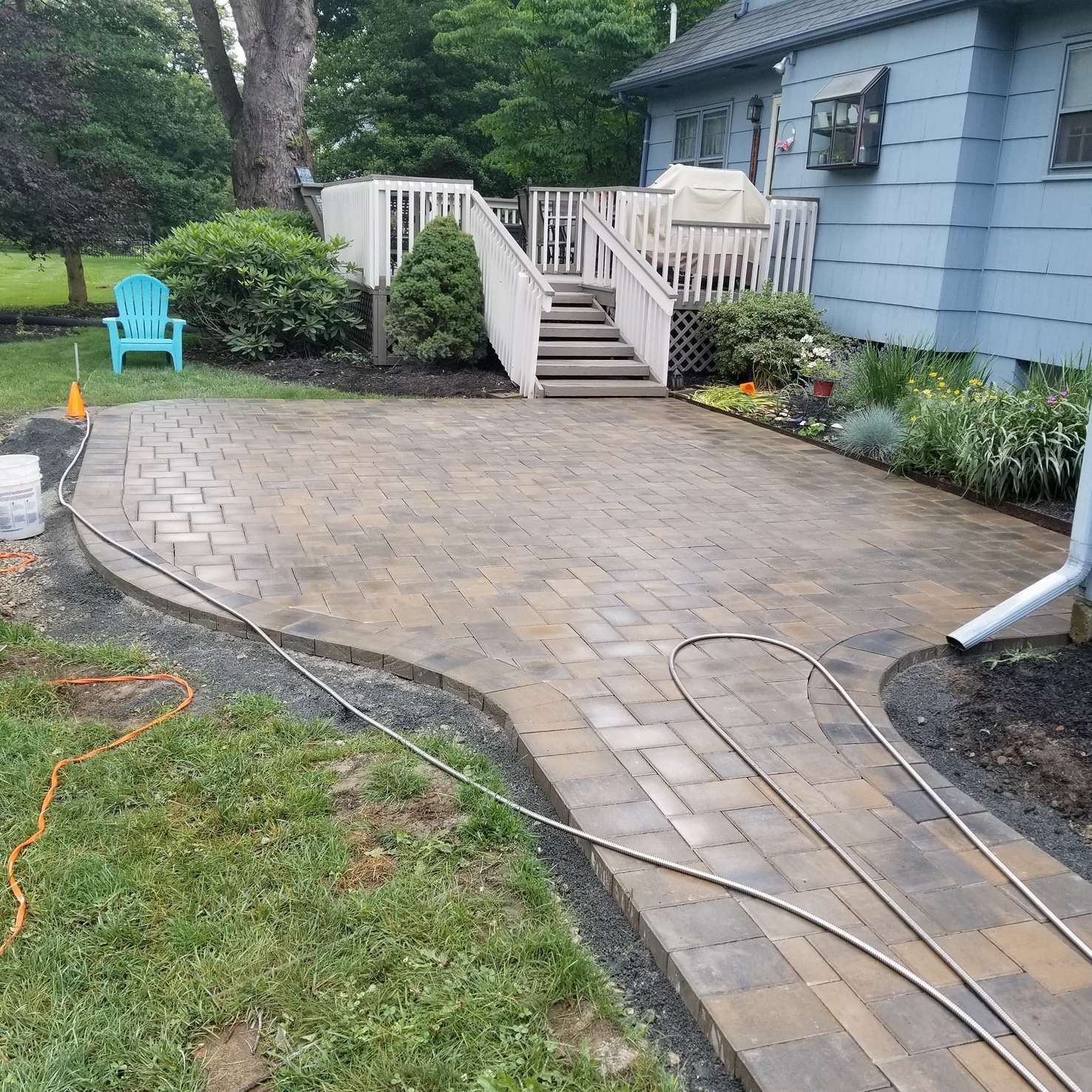 A patio with stairs leading to a deck and a blue chair