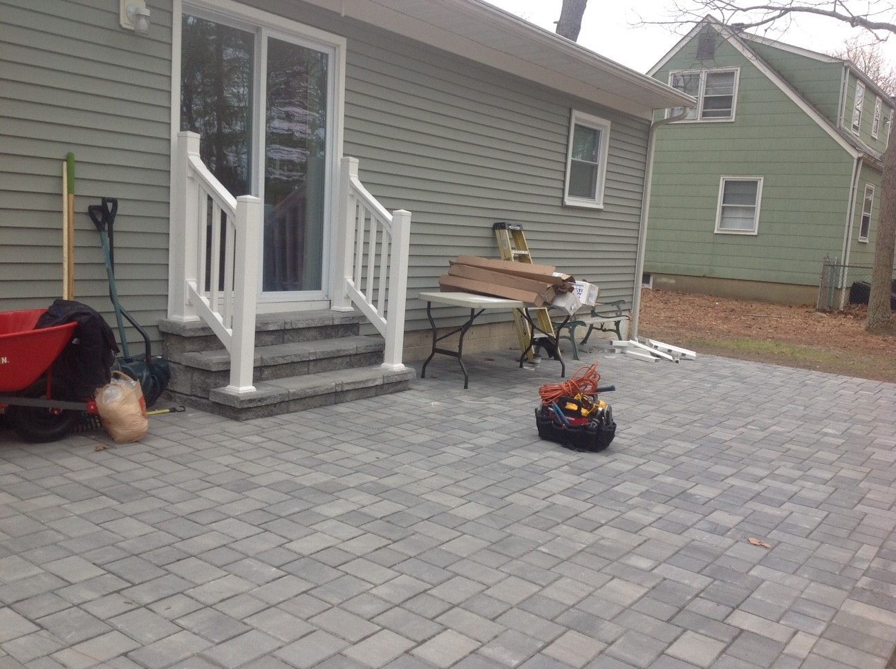 A patio with stairs and a table in front of a house.