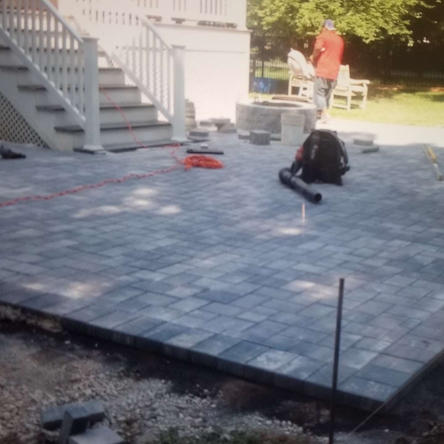 A man is standing on a brick patio next to stairs.