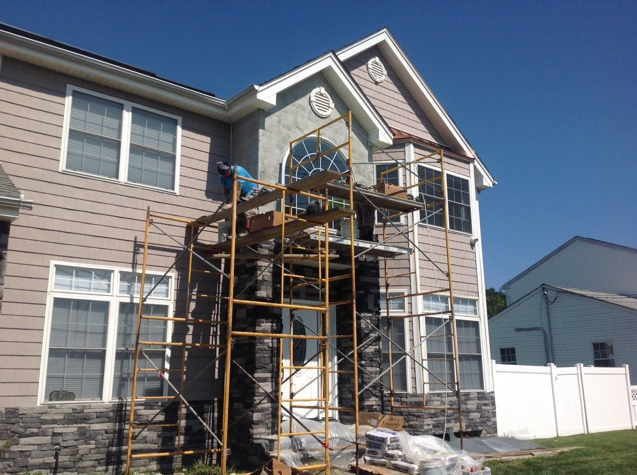 A large house is being painted with scaffolding in front of it.