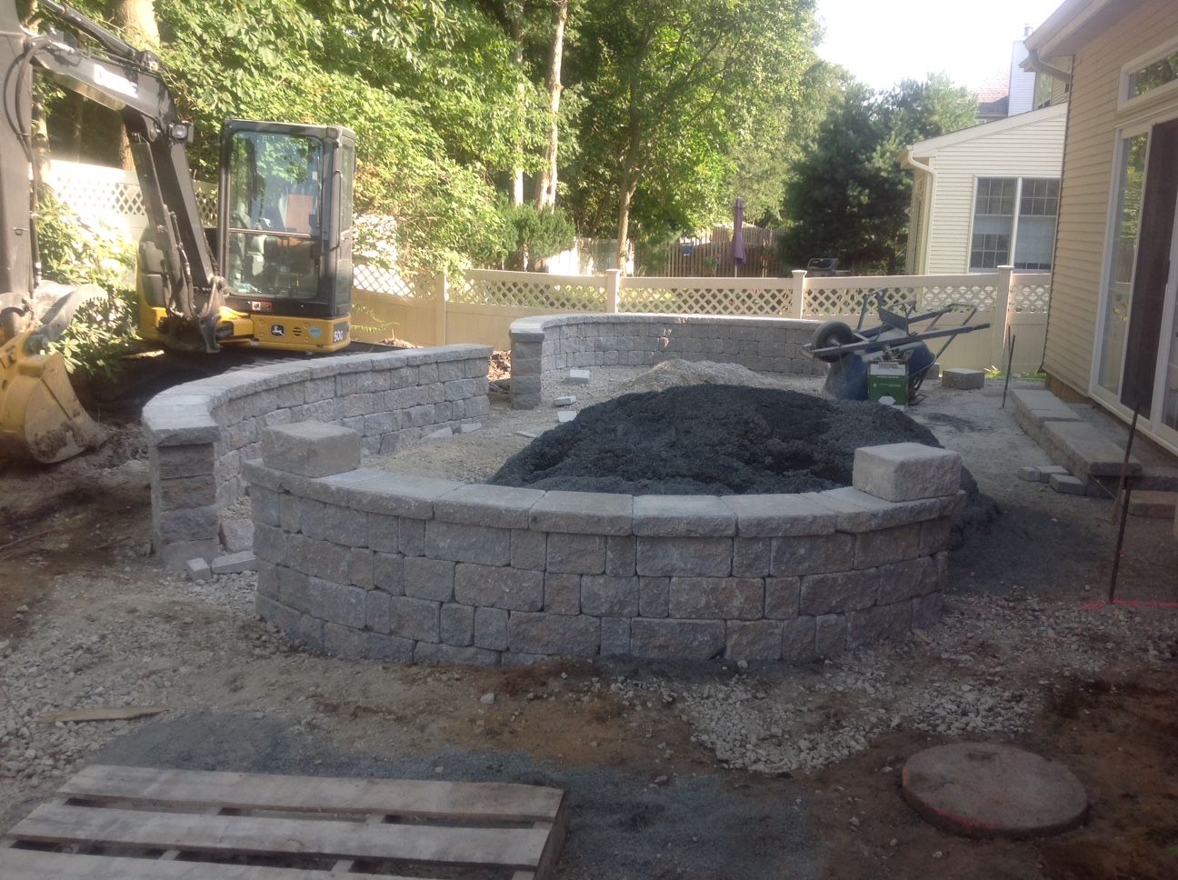 A circular brick wall is being built in front of a house.