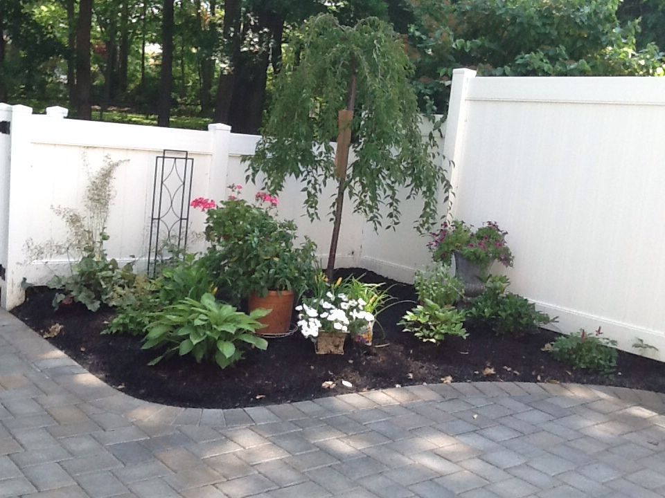 A white fence surrounds a garden with potted plants