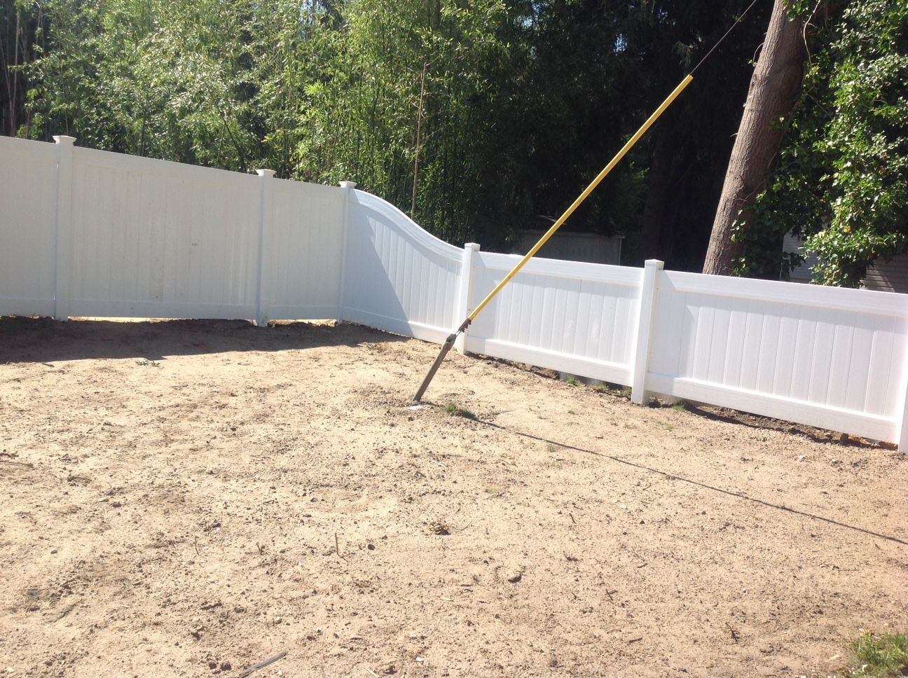 A white fence with a yellow rake in the middle of it