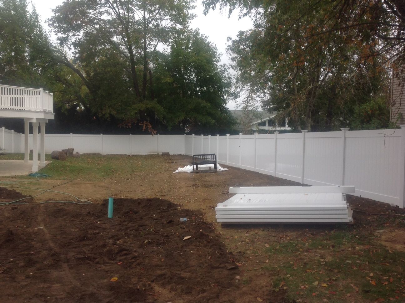There is a white fence in the backyard of a house.
