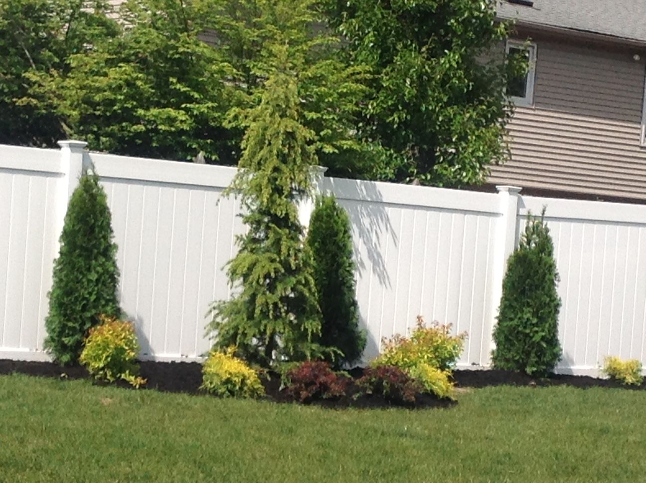 A white fence with trees in front of it