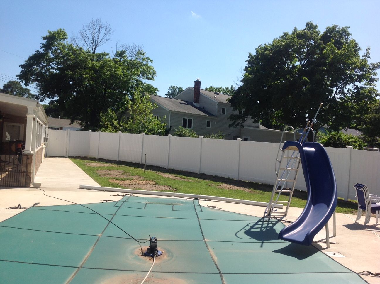 A swimming pool with a slide and ladder in the backyard