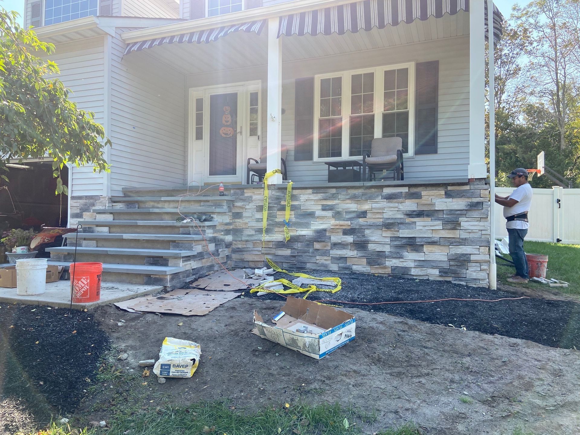 A man is working on the front porch of a house.