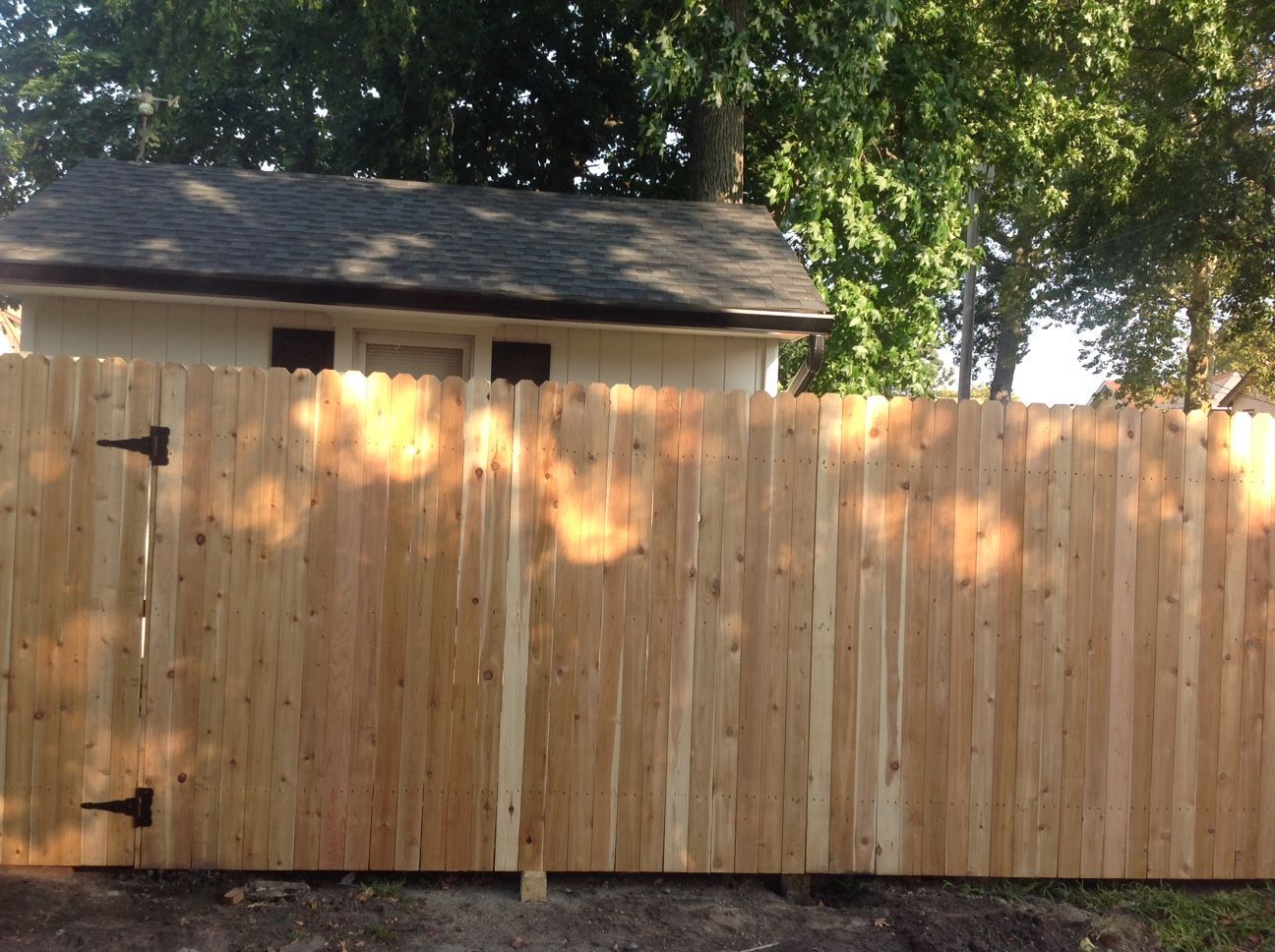 A wooden fence with a gate in front of a house
