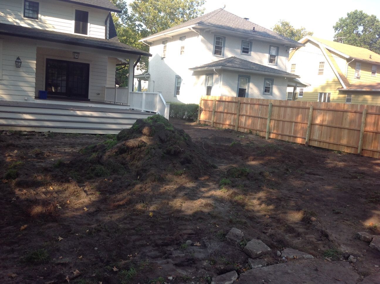 A backyard with a wooden fence and a house in the background