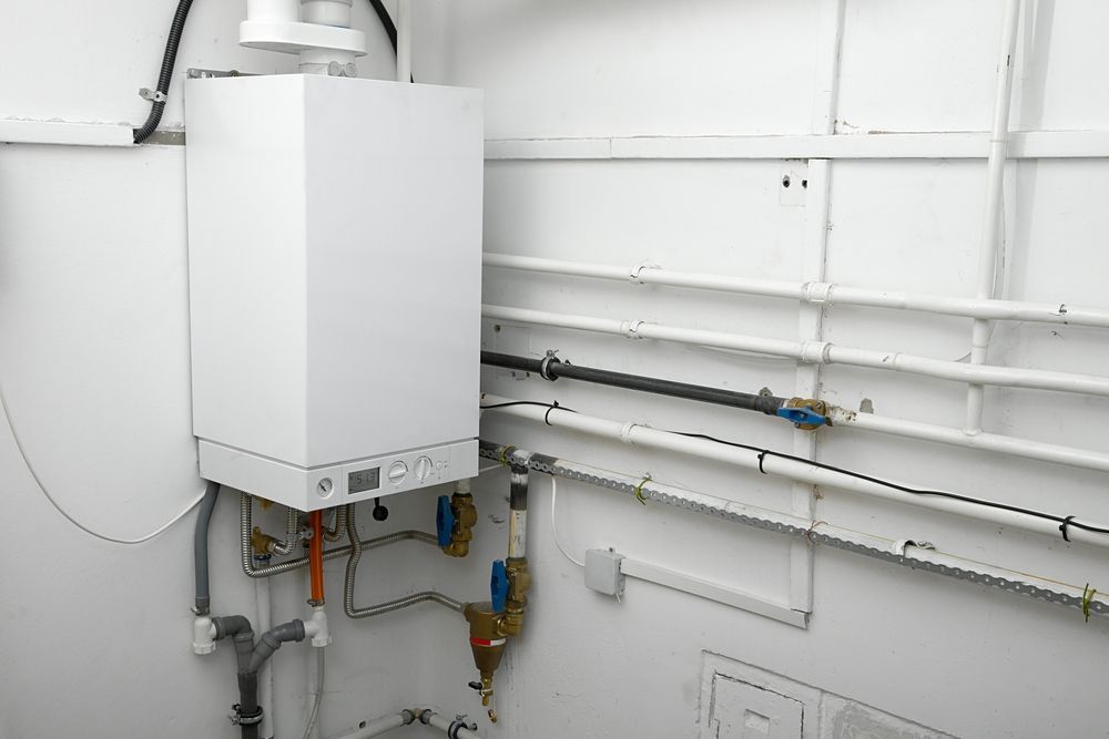White Boiler on A White Wall with Connected Pipes and Valves — 2 Foote Plumbing & Gas in Darwin, NT