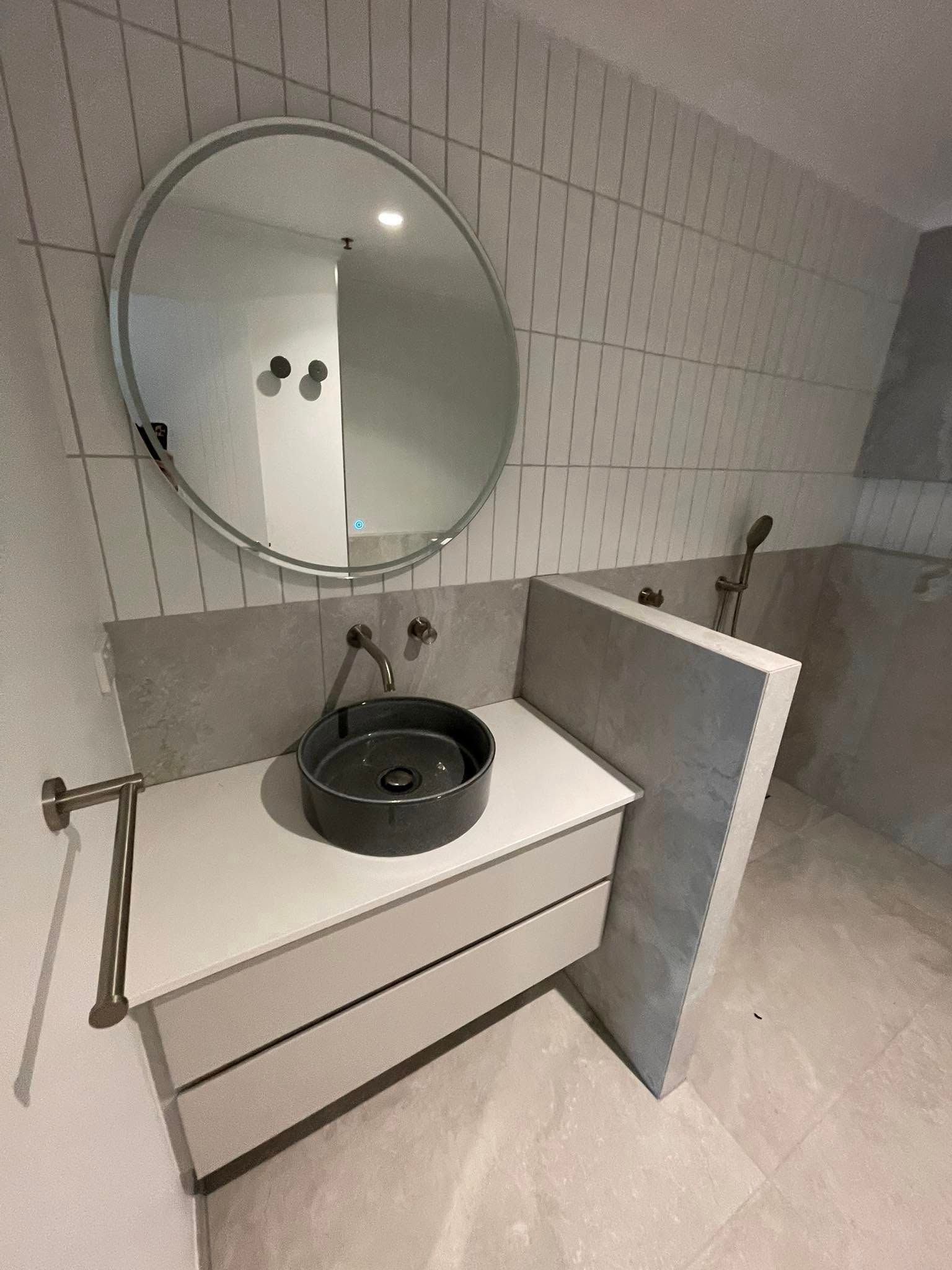 Modern Bathroom with A Round Mirror, Dark Sink, and Light Cabinetry — 2 Foote Plumbing & Gas in Darwin, NT