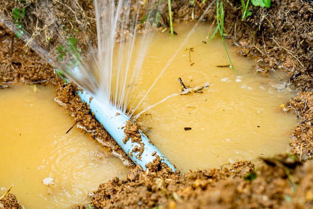 Damaged Blue Pipe Spraying Water in Muddy Ground — 2 Foote Plumbing & Gas in Darwin, NT