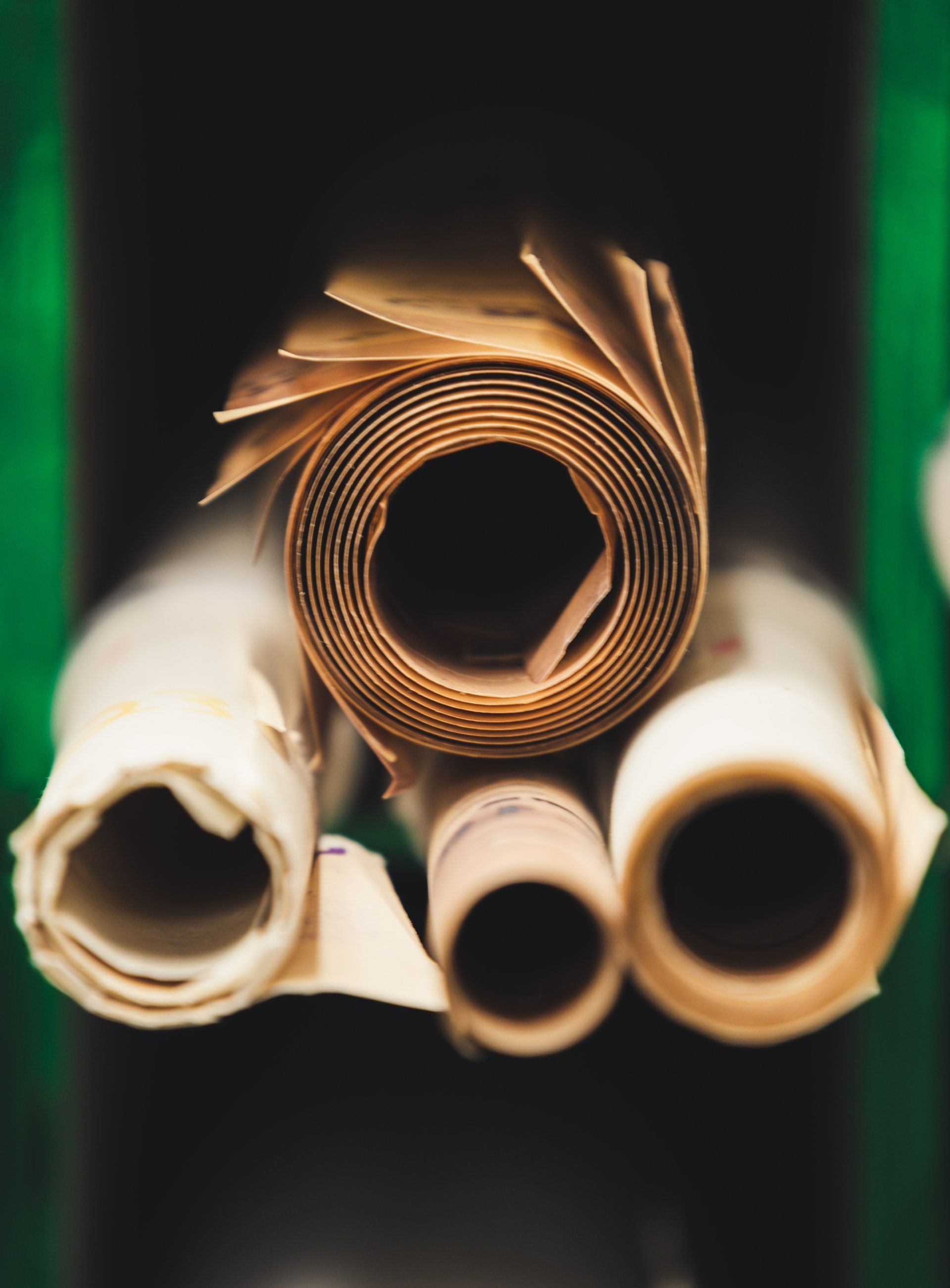 Rolled up parchment scrolls; brown, yellowed paper, stacked in dark shelving.