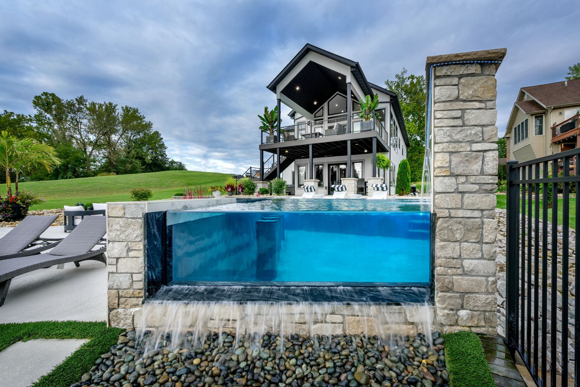 a large swimming pool with a waterfall in front of a house .