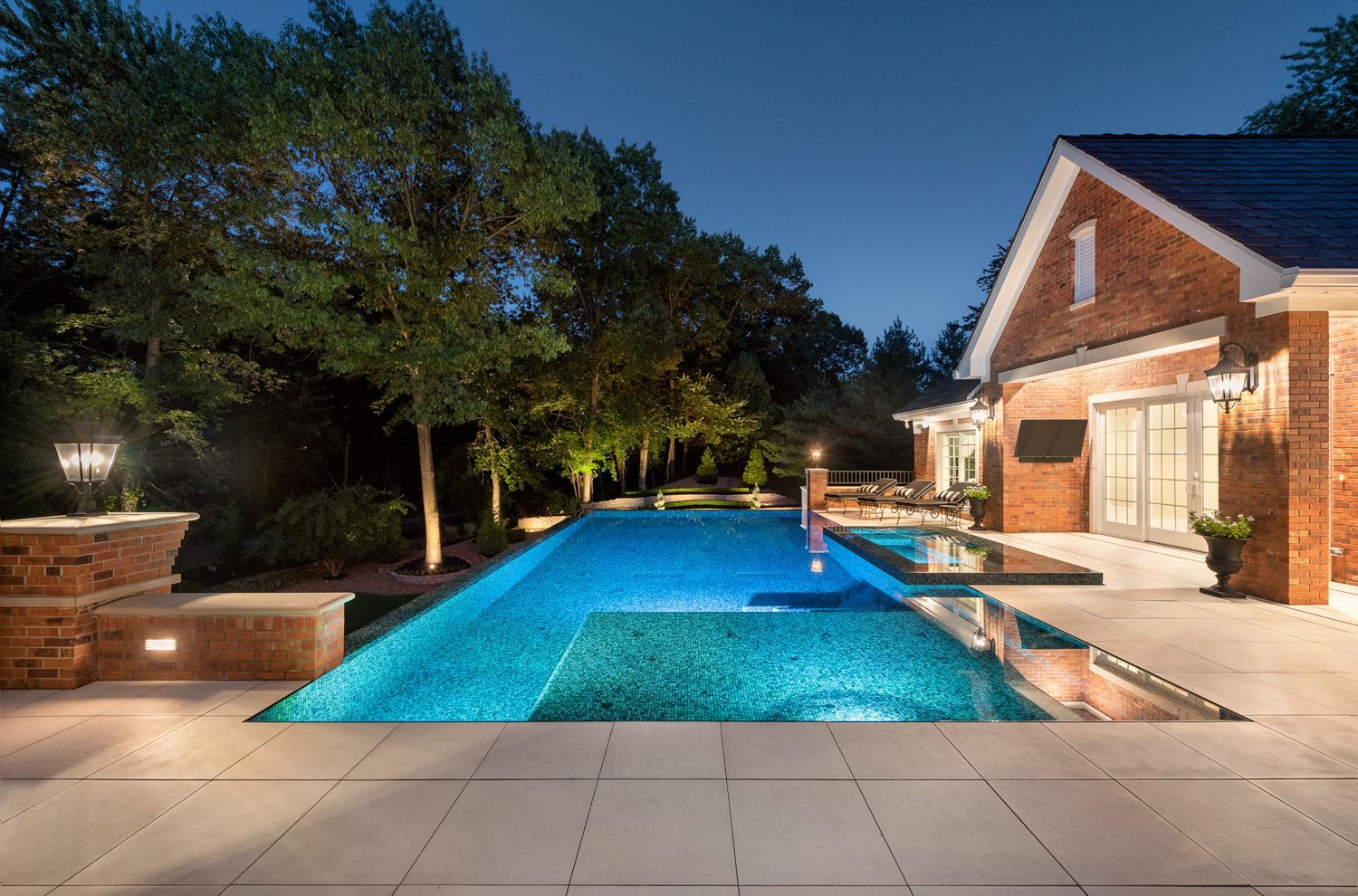 a large swimming pool in front of a brick house at night .