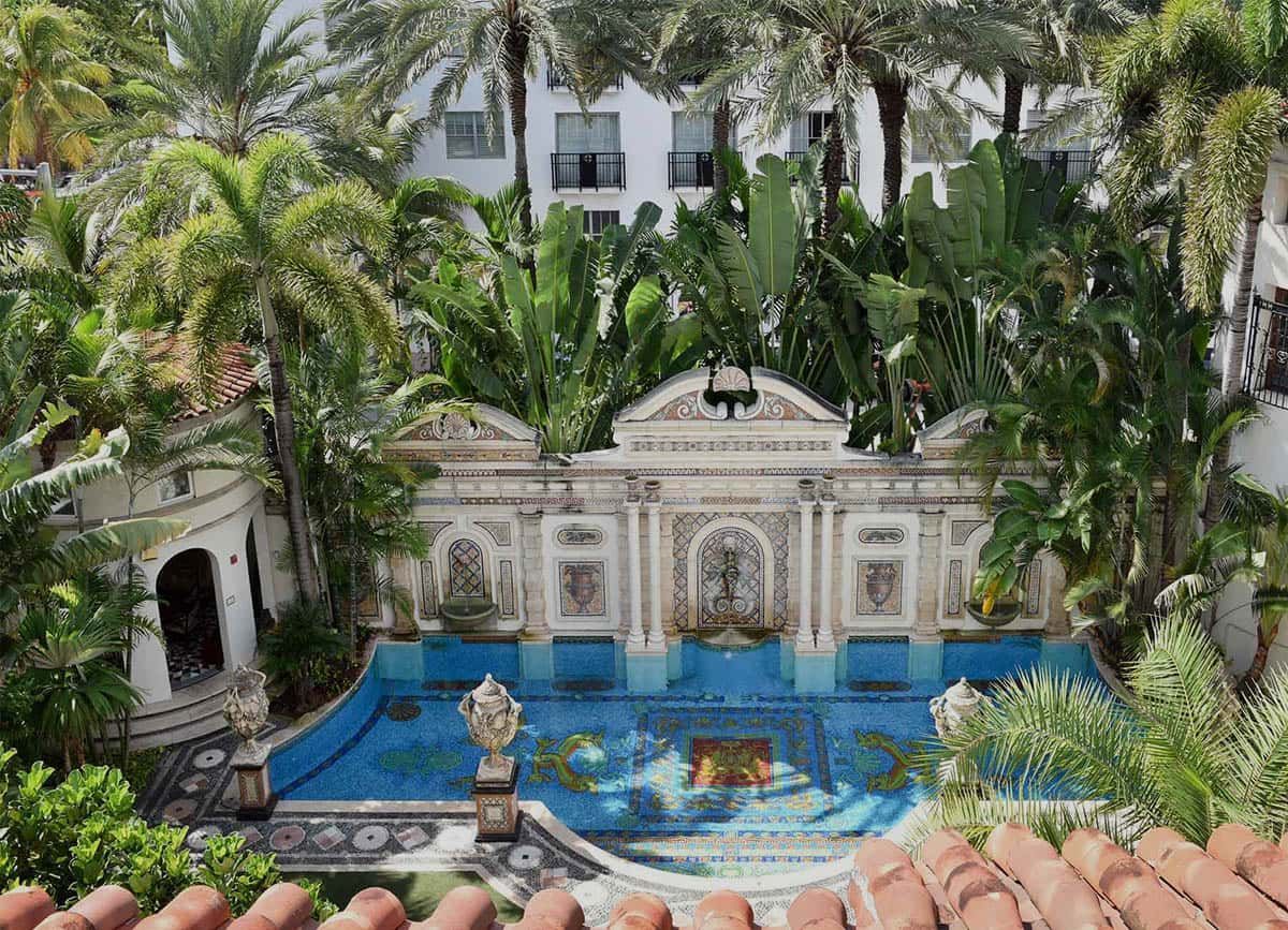 Ornate courtyard with mosaic pool and fountain, lush tropical plants, and architectural details; Miami, Florida.
