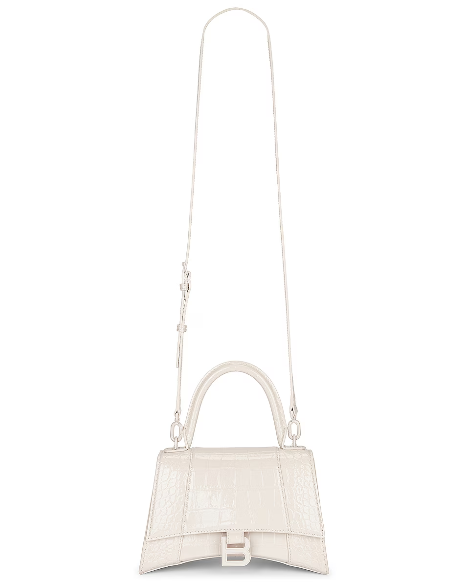White Balenciaga handbag with a top handle and long shoulder strap, featuring a textured surface and silver hardware.
