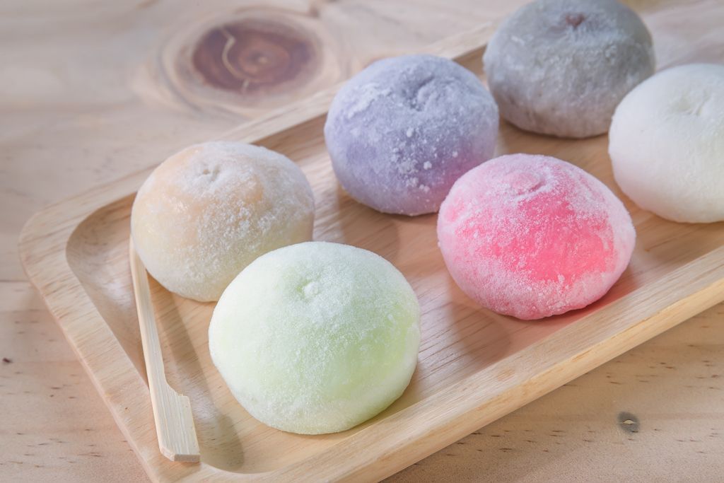there are many different types of mochi on a wooden tray .