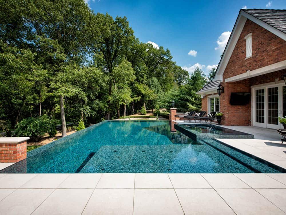 a large swimming pool is surrounded by trees and a brick house .