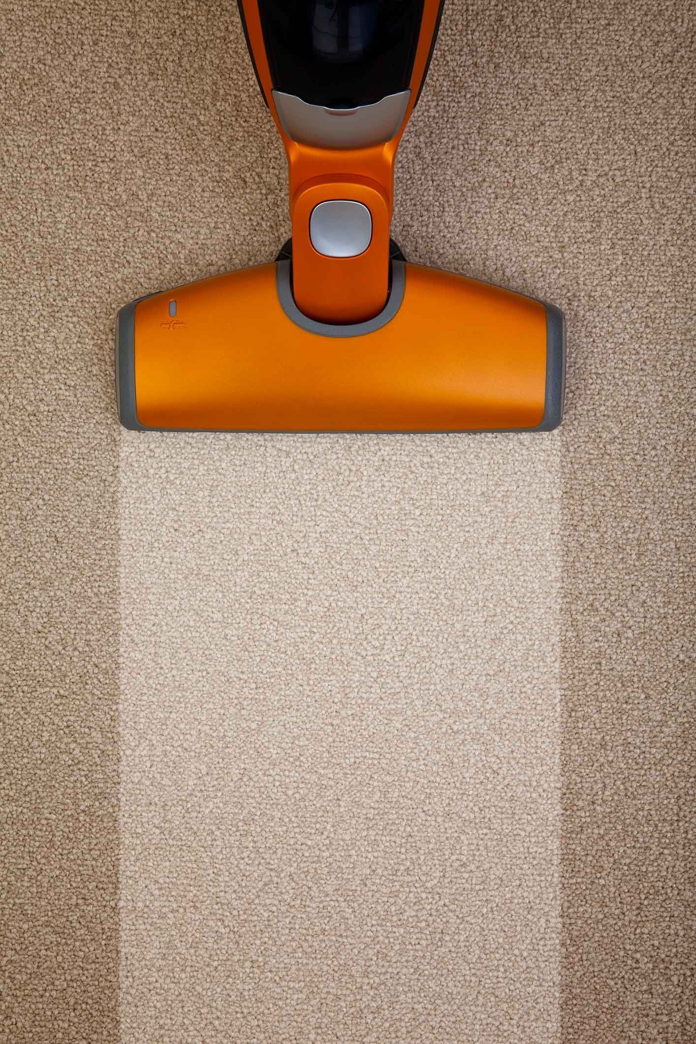 A close up of a vacuum cleaner cleaning a carpet.