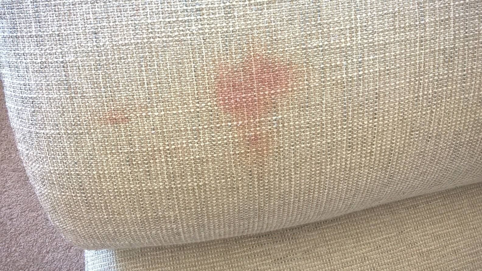 A close up of a couch with a stain on it.