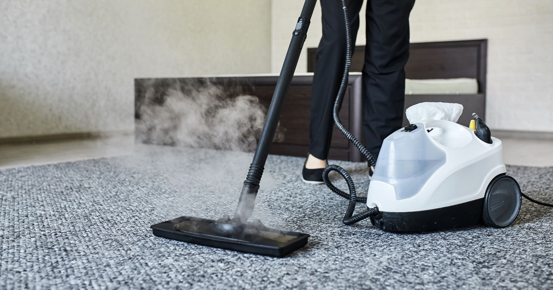 Cleaning service company employee removing dirt from carpet in flat with professional steam cleaner
