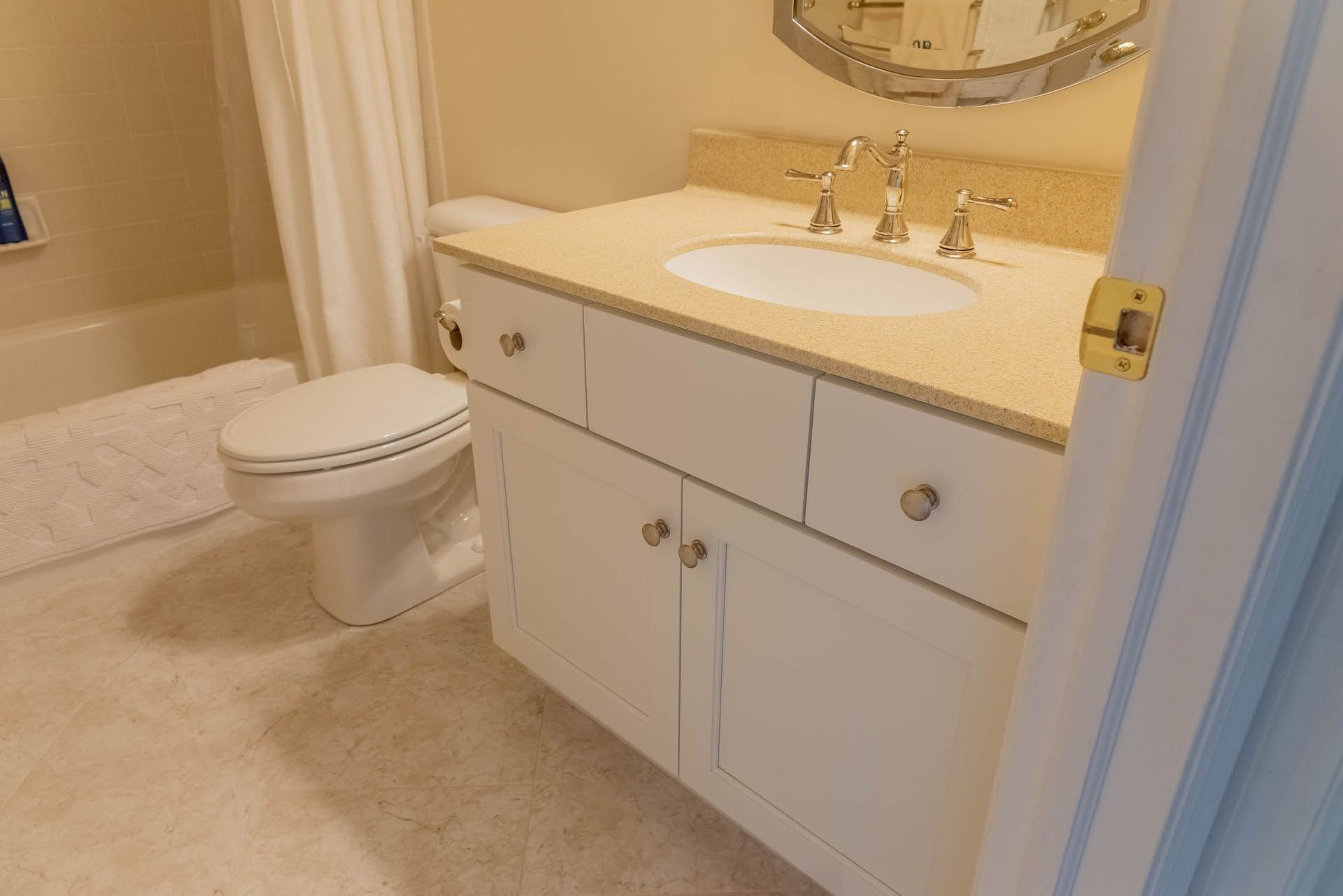 Bathroom vanity with white sink, mirror, and toilet beside a beige carpeted floor