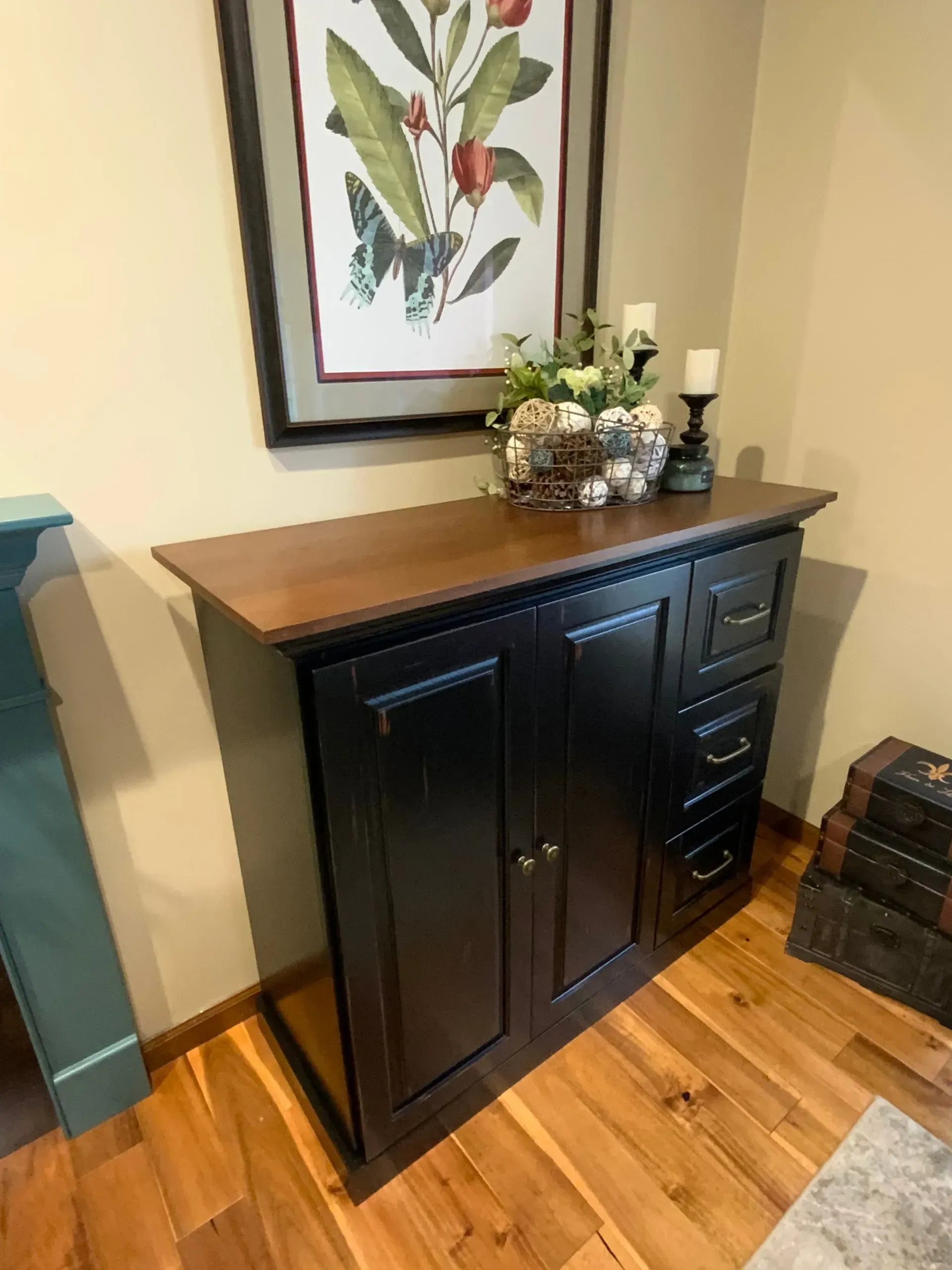 A black cabinet with drawers and a picture on top of it in a living room.