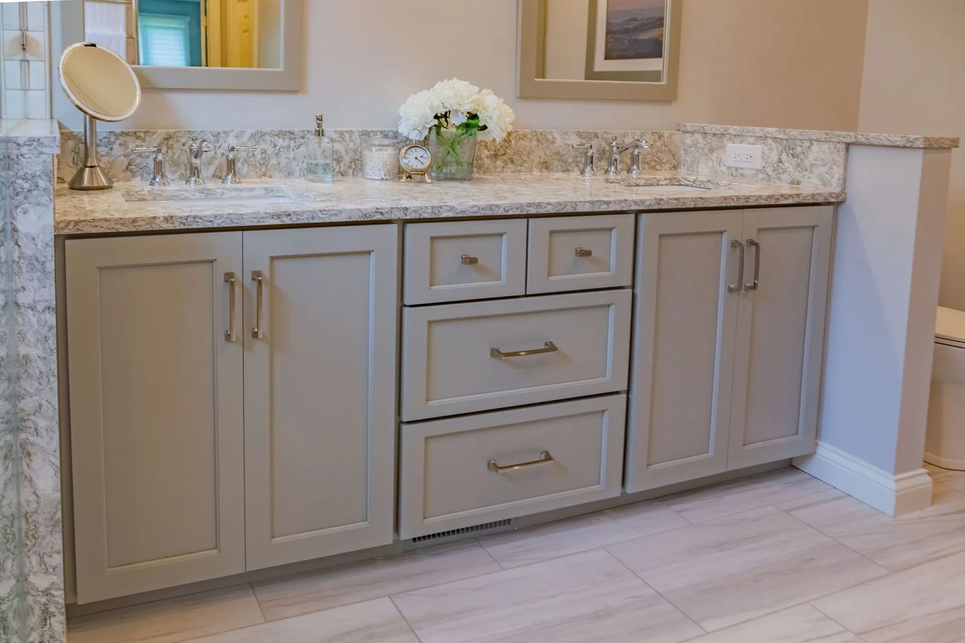 Bathroom vanity with light gray cabinets, granite countertop, and two sinks.