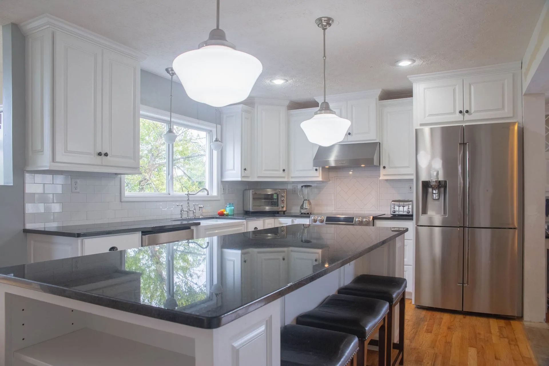 Modern white kitchen with black countertop island and stainless steel appliances.
