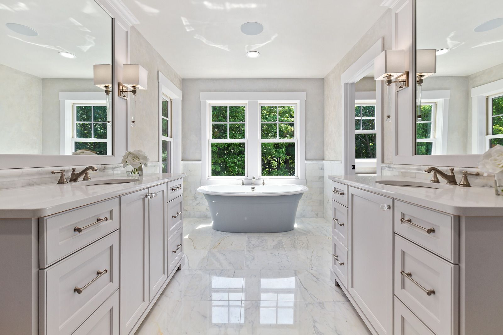 A bathroom with two sinks , two mirrors and a tub.
