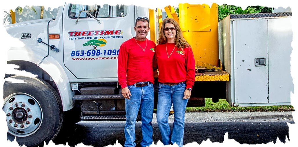 Two people in red shirts and jeans stand next to a white truck Two people in red shirts and jeans stand next to a white truck