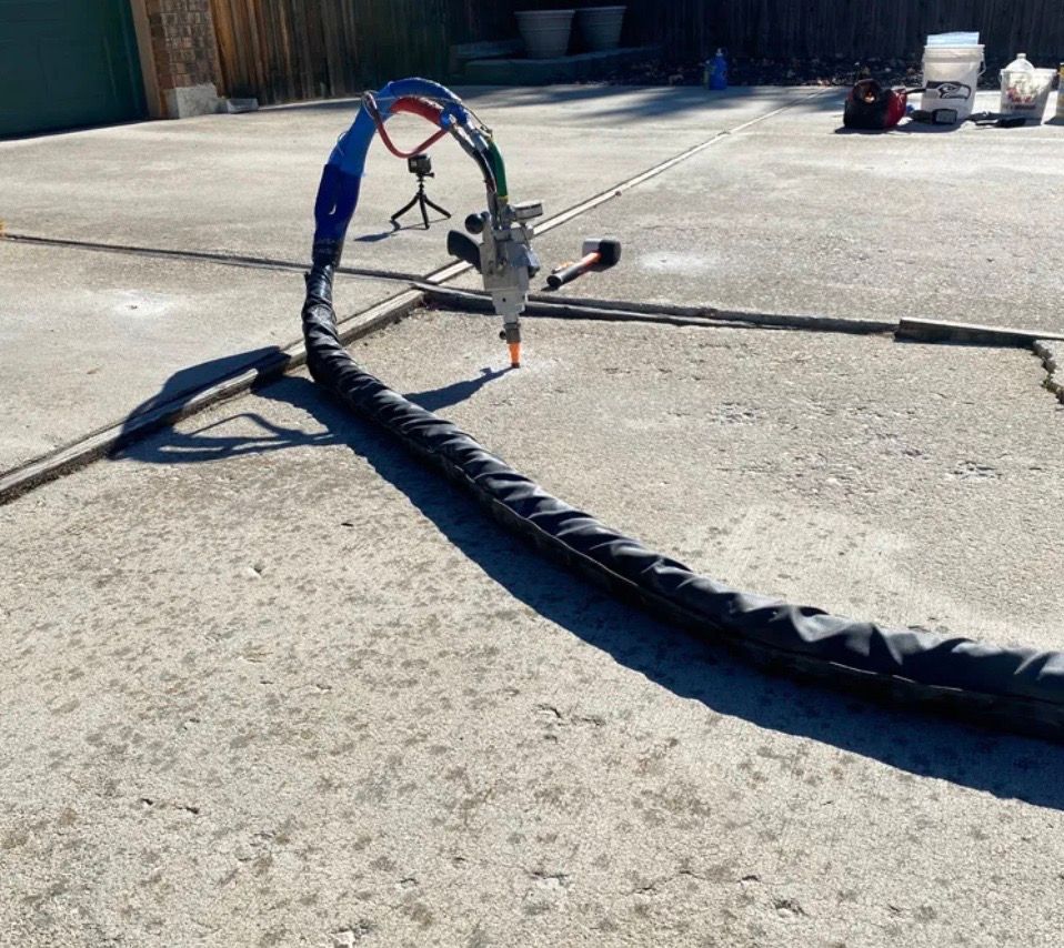 Machine spraying sealant on cracked asphalt pavement outdoors.