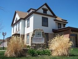 White building, Cliff North Memorial Chapel sign, brown roof, stone base, clear sky.
