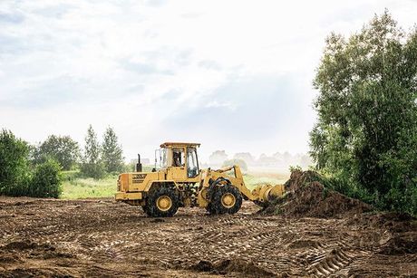 large yellow wheel loader aligns a piece of land for a new building