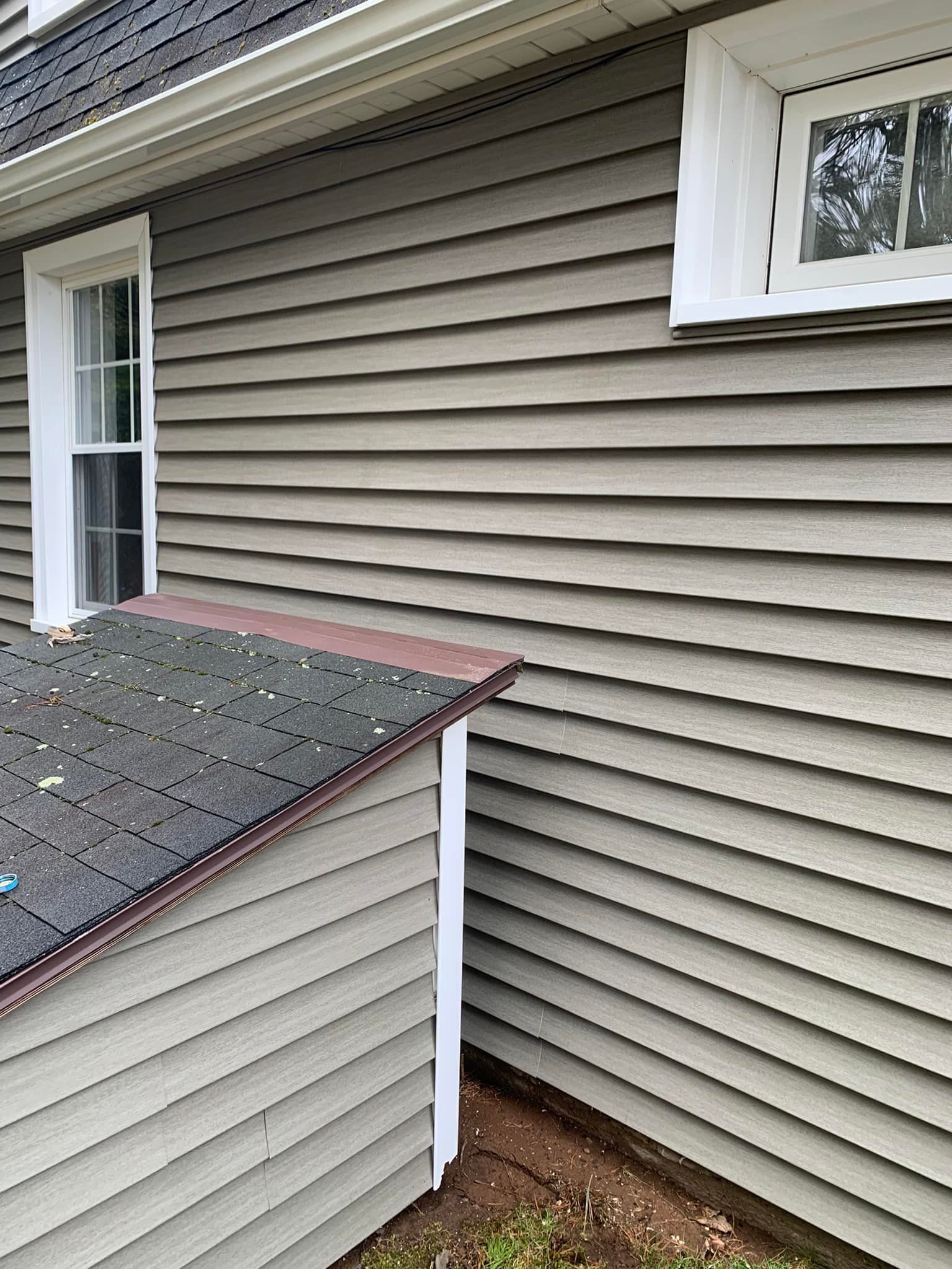 A house with a siding and a window on the side of it.