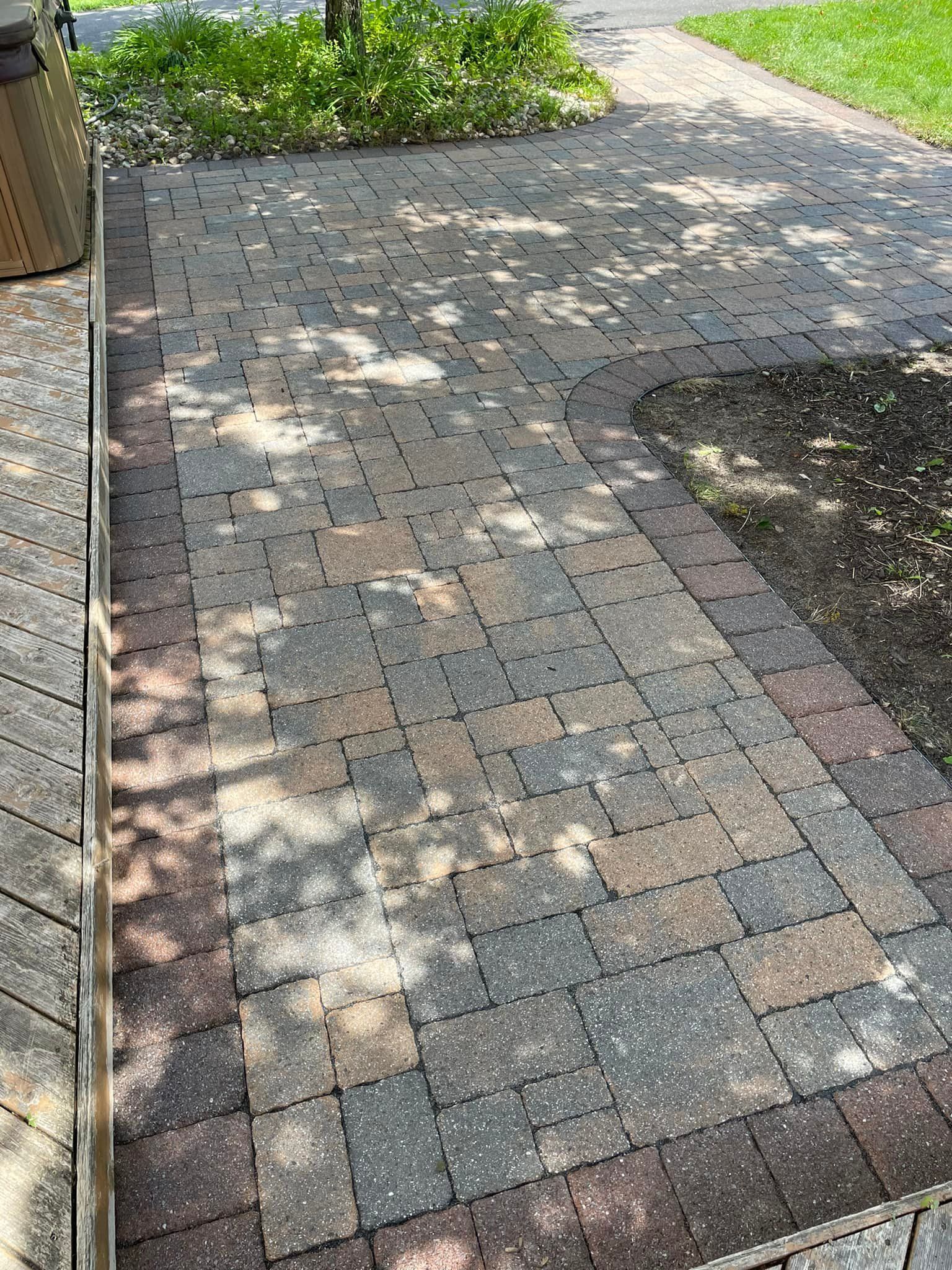 A brick walkway with a wooden deck in the background.