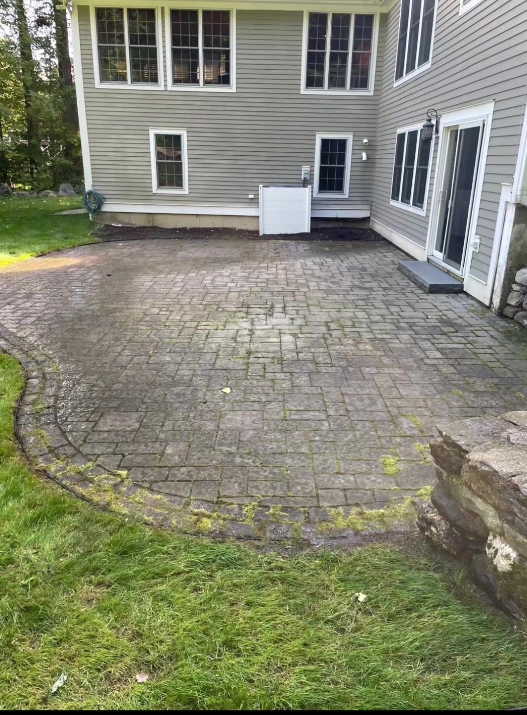 A patio in front of a house with a lot of moss on it.
