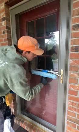 A man is cleaning a door with a squeegee.
